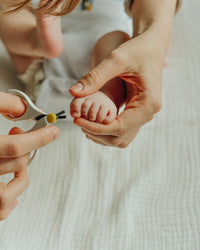 Cuidado del recién nacido cortando las uñas del pie con tijeras de bebé 
